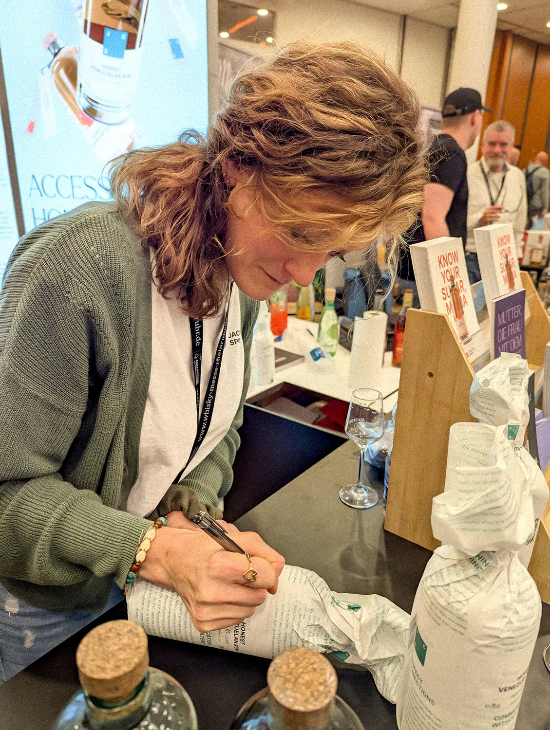 Nina Vorster signiert eine Jack Crap Spirits Rumflasche auf einem Messestand
